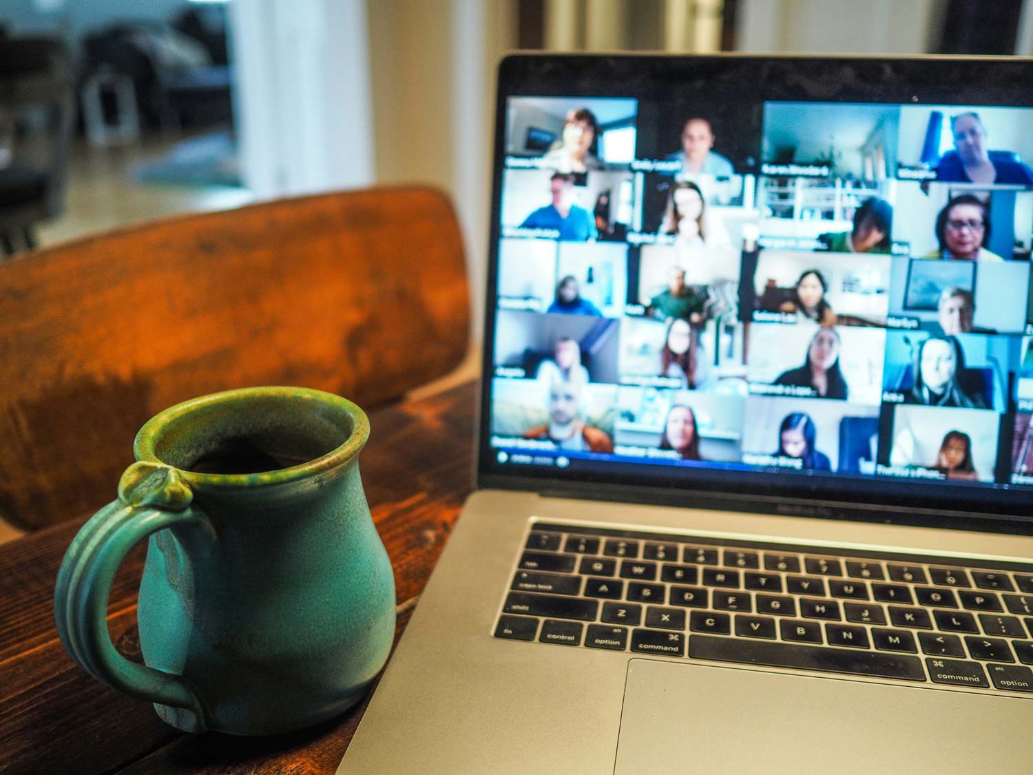 Laptop that's displaying a video meeting, with coffee cup on the side